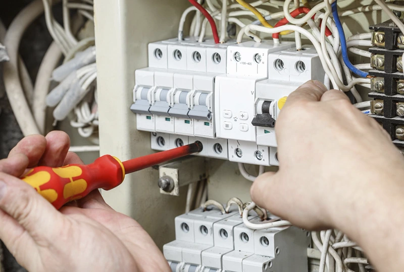 manos con destornillador manipulando cuadro luz